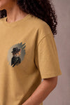 Woman wearing a custom faded mustard tee with a printed design